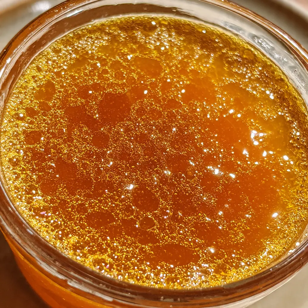 Close-up of the simmering pumpkin juice in a pot, showing the cinnamon sticks and ginger slices infusing.